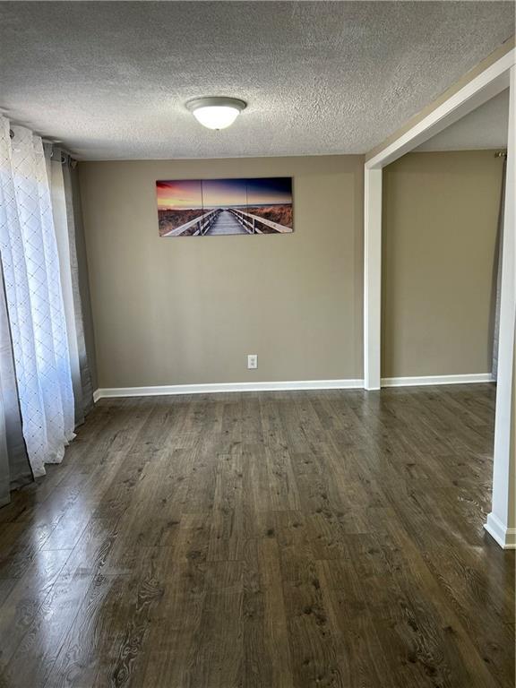 unfurnished dining area with dark wood-type flooring and a textured ceiling