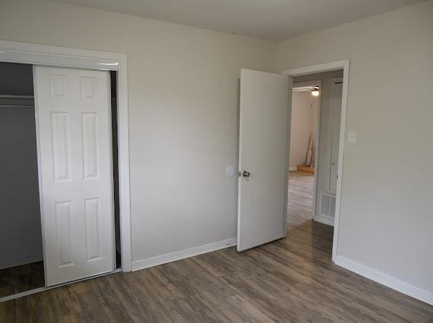 unfurnished bedroom with baseboards, a closet, and wood finished floors