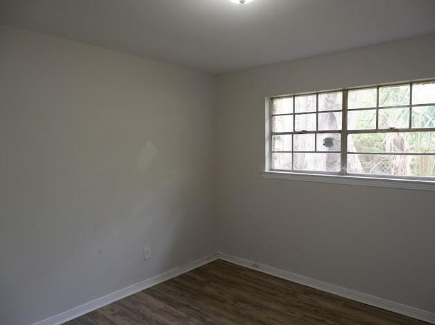 unfurnished room featuring dark wood-type flooring and baseboards