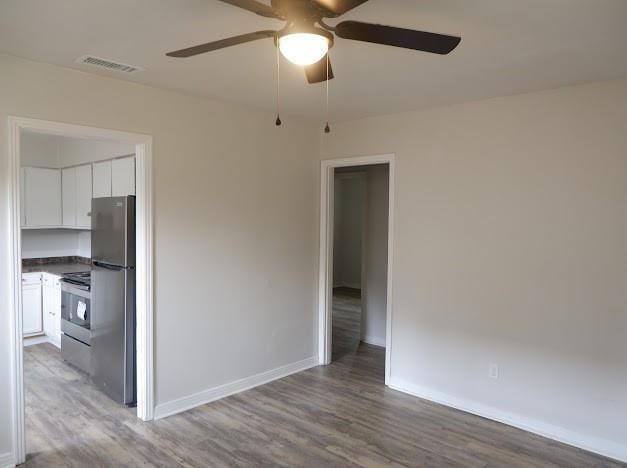 unfurnished room featuring baseboards, a ceiling fan, visible vents, and wood finished floors