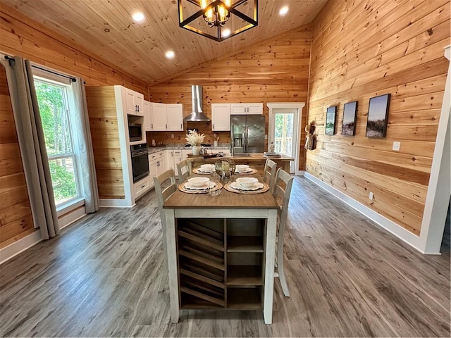 1401 Osprey Ln, Dauphin Island, AL 36528 - kitchen with wall chimney range hood, oven, wood walls, and stainless steel refrigerator with ice dispenser