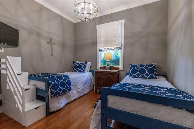 bedroom featuring wood finished floors, a chandelier, and ornamental molding