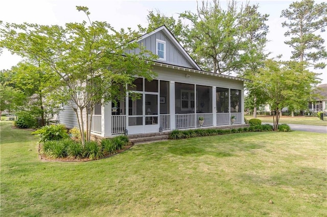 view of front of house featuring a sunroom, a front lawn, and board and batten siding