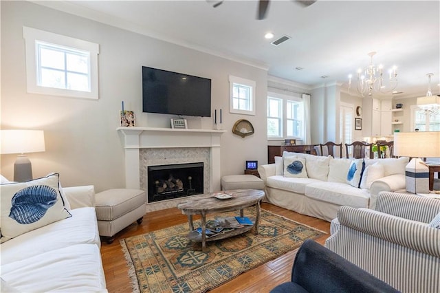 living room featuring a chandelier, ornamental molding, wood finished floors, a fireplace, and recessed lighting