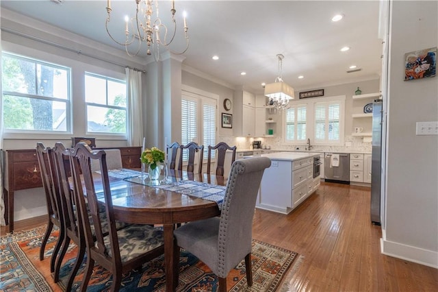 dining space with a chandelier, ornamental molding, wood finished floors, recessed lighting, and baseboards