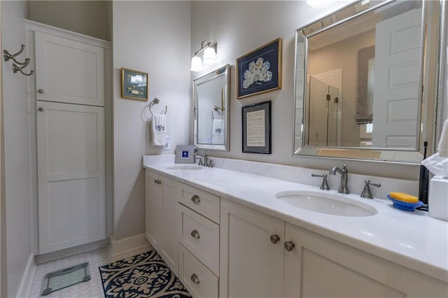 bathroom with a tile shower, double vanity, tile patterned flooring, and baseboards