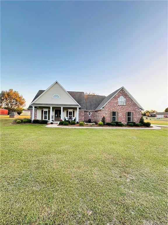 greek revival house featuring covered porch and a front lawn