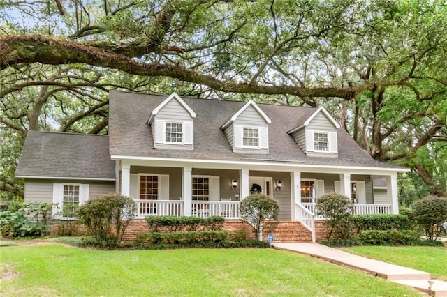 cape cod home featuring a shingled roof, a porch, and a front lawn