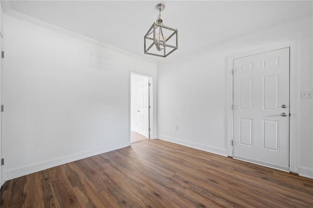 spare room with crown molding, dark hardwood / wood-style flooring, and a chandelier