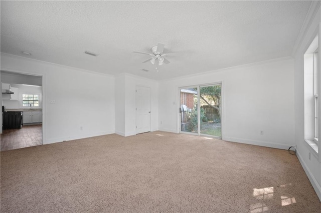 carpeted empty room featuring a textured ceiling, ornamental molding, ceiling fan, and plenty of natural light