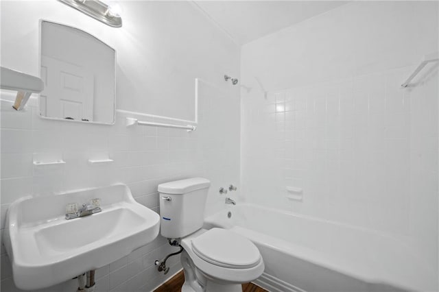 full bathroom featuring tile walls, sink, tiled shower / bath, and toilet