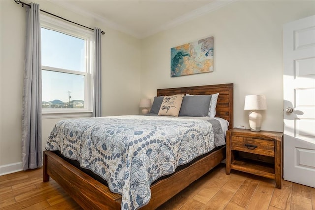 bedroom featuring light wood finished floors, baseboards, and crown molding