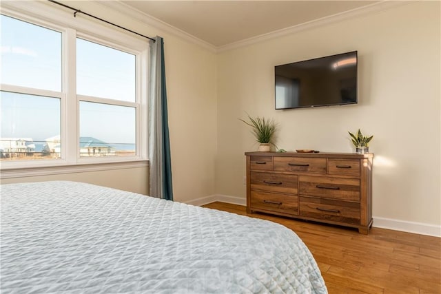 bedroom featuring ornamental molding, light wood-type flooring, and baseboards