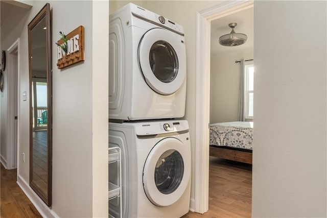laundry area featuring light wood-type flooring, stacked washer and dryer, and laundry area