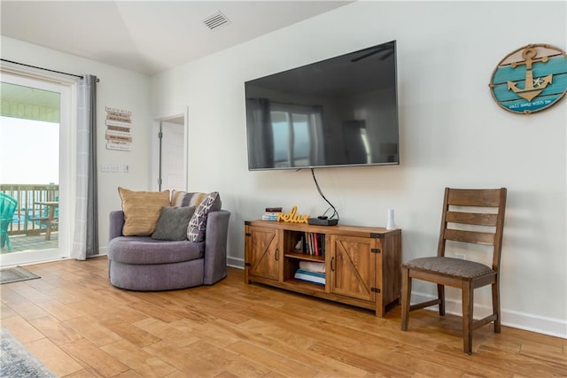 sitting room with light wood-type flooring, visible vents, and baseboards