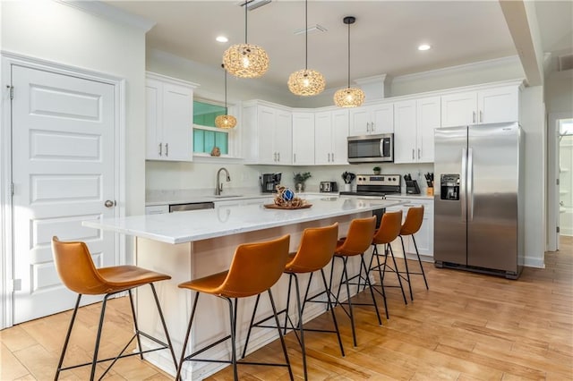 kitchen with appliances with stainless steel finishes, a kitchen island, white cabinetry, and pendant lighting