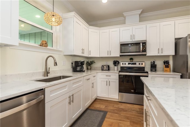 kitchen with stainless steel appliances, hanging light fixtures, a sink, and white cabinetry