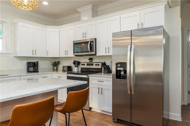 kitchen featuring light stone counters, wood finished floors, white cabinetry, appliances with stainless steel finishes, and crown molding