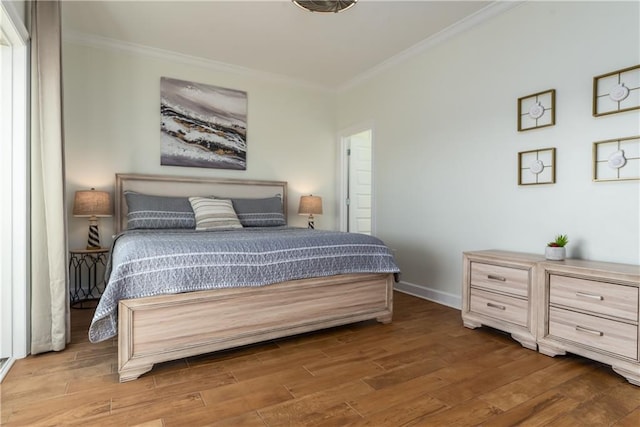 bedroom featuring baseboards, ornamental molding, and wood finished floors