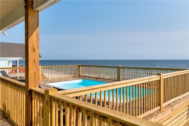 deck featuring a water view, a hot tub, and a view of the beach