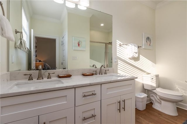 ensuite bathroom featuring double vanity, ornamental molding, a stall shower, a sink, and wood finished floors
