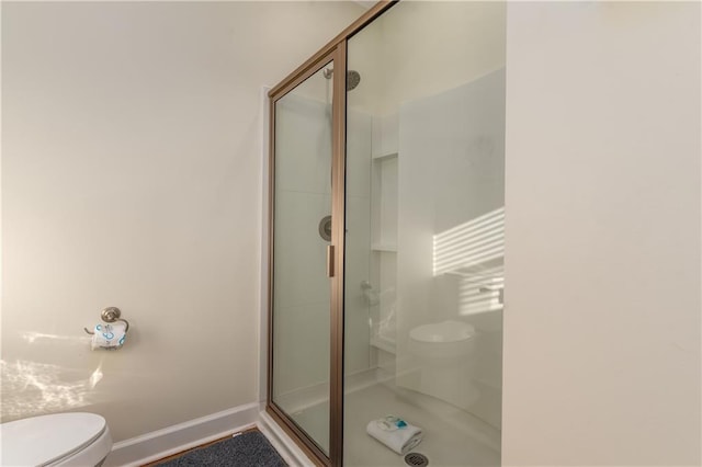 bathroom featuring a shower stall, toilet, and baseboards
