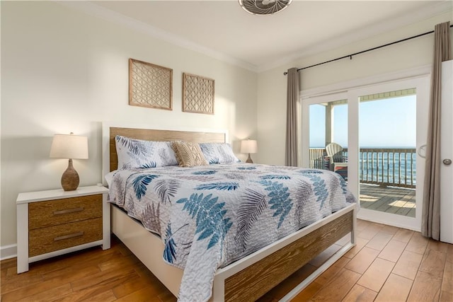 bedroom featuring access to exterior, a water view, crown molding, and wood finished floors