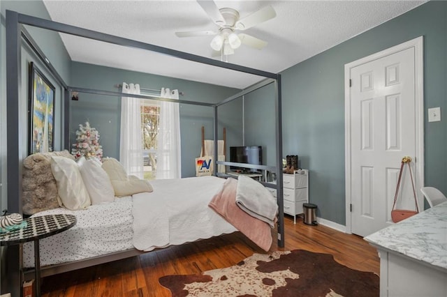 bedroom with a textured ceiling, hardwood / wood-style flooring, and ceiling fan