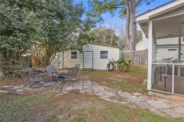 view of yard featuring an outdoor structure, a patio area, and a sunroom