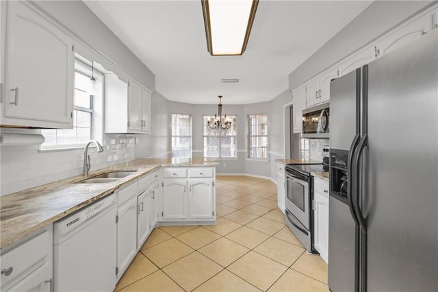 kitchen with sink, stainless steel appliances, white cabinets, decorative light fixtures, and kitchen peninsula
