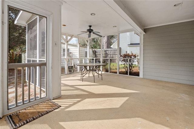 unfurnished sunroom featuring beam ceiling and ceiling fan