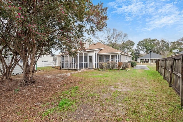 rear view of house featuring a carport, a sunroom, and a lawn