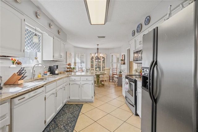 kitchen featuring kitchen peninsula, stainless steel appliances, white cabinets, and a healthy amount of sunlight