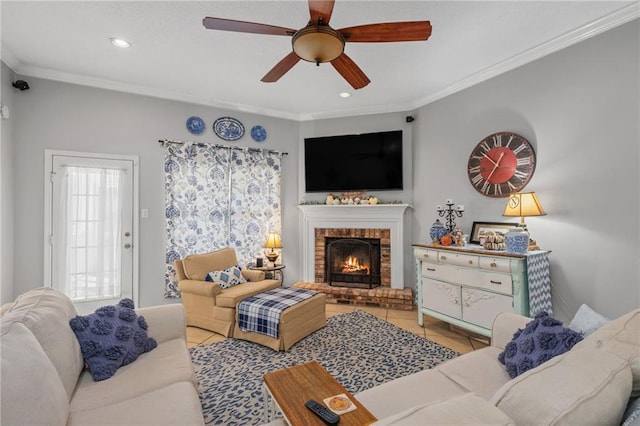 living room with a brick fireplace, ceiling fan, and crown molding