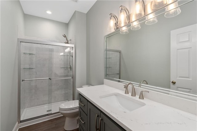 bathroom with a shower with door, toilet, vanity, and wood-type flooring