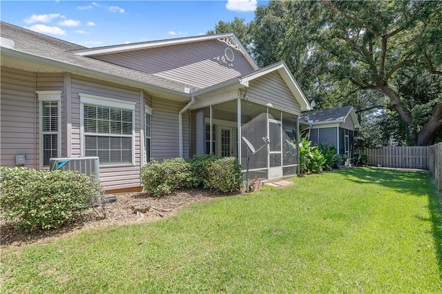 exterior space with central AC, a sunroom, and a yard