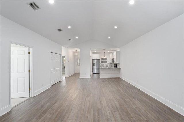 unfurnished living room featuring wood-type flooring and vaulted ceiling