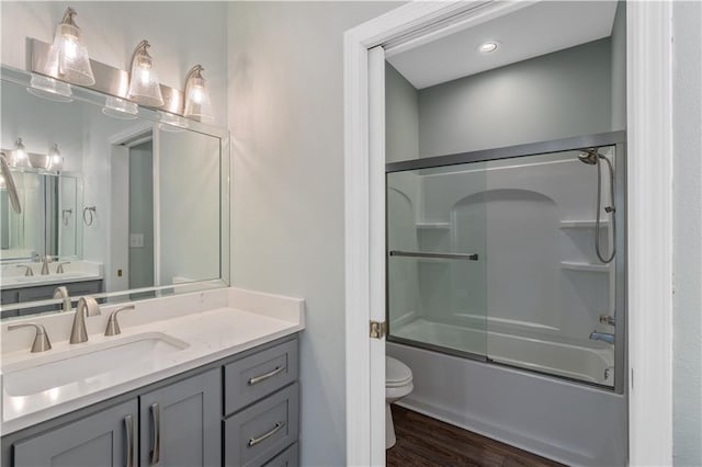 full bathroom with enclosed tub / shower combo, toilet, vanity, and wood-type flooring