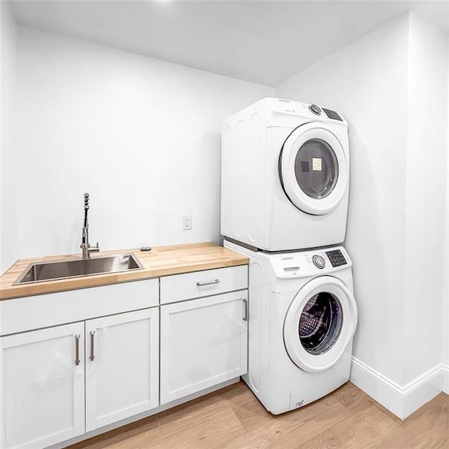 7498 Pinehill Rd, Daphne, AL 36526 - washroom featuring stacked washing machine and dryer, cabinet space, and light wood-style floors