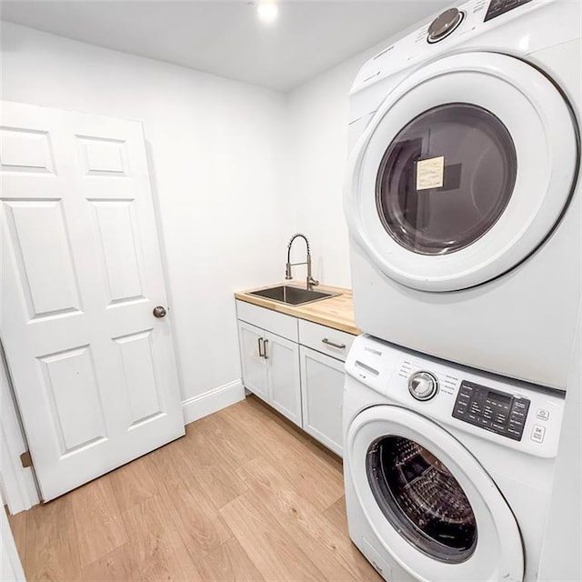 7498 Pinehill Rd, Daphne, AL 36526 - washroom featuring stacked washer and clothes dryer, cabinet space, and light wood-style floors