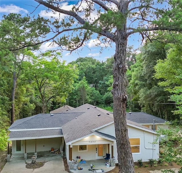 7498 Pinehill Rd, Daphne, AL 36526 - rear view of house featuring roof with shingles, a patio, concrete driveway, and an attached carport