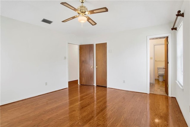 10437 Traci Dr, Semmes, AL 36575 - unfurnished bedroom with connected bathroom, ceiling fan, baseboards, wood finished floors, and visible vents