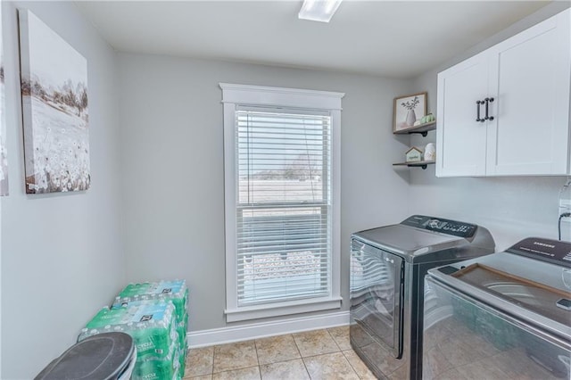 laundry area featuring cabinets, light tile patterned floors, and washing machine and clothes dryer