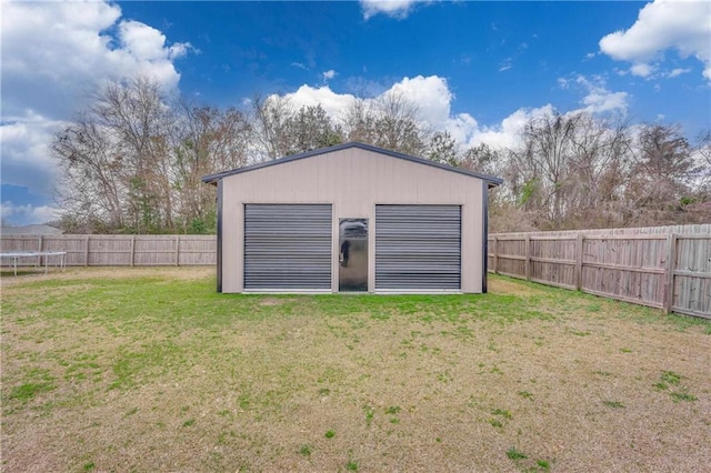 view of outdoor structure featuring a trampoline, a garage, and a lawn