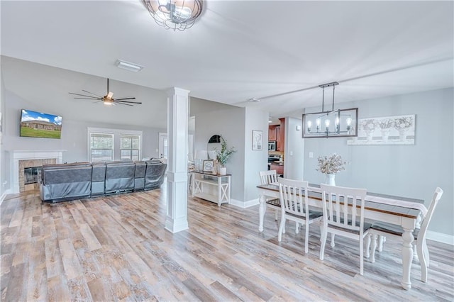 dining room featuring ceiling fan, lofted ceiling, light wood-type flooring, and ornate columns