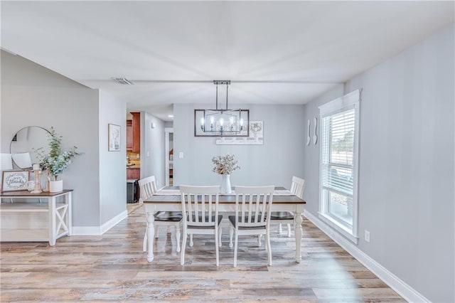 dining area with a chandelier and light hardwood / wood-style flooring