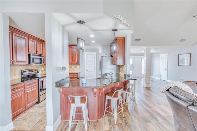 kitchen featuring stainless steel appliances, decorative light fixtures, kitchen peninsula, and decorative columns