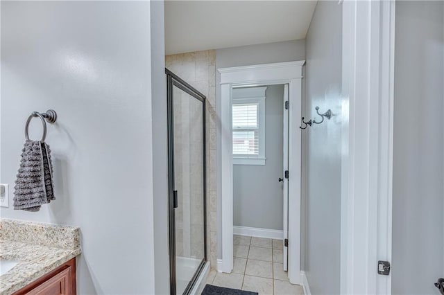 bathroom with a shower with door, vanity, and tile patterned floors