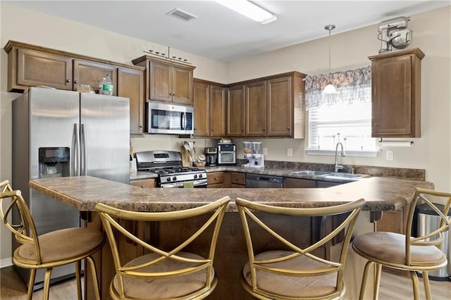 kitchen featuring pendant lighting, stainless steel appliances, light hardwood / wood-style floors, and sink