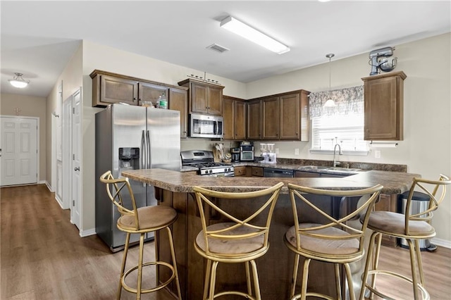 kitchen featuring pendant lighting, sink, a breakfast bar area, stainless steel appliances, and dark wood-type flooring